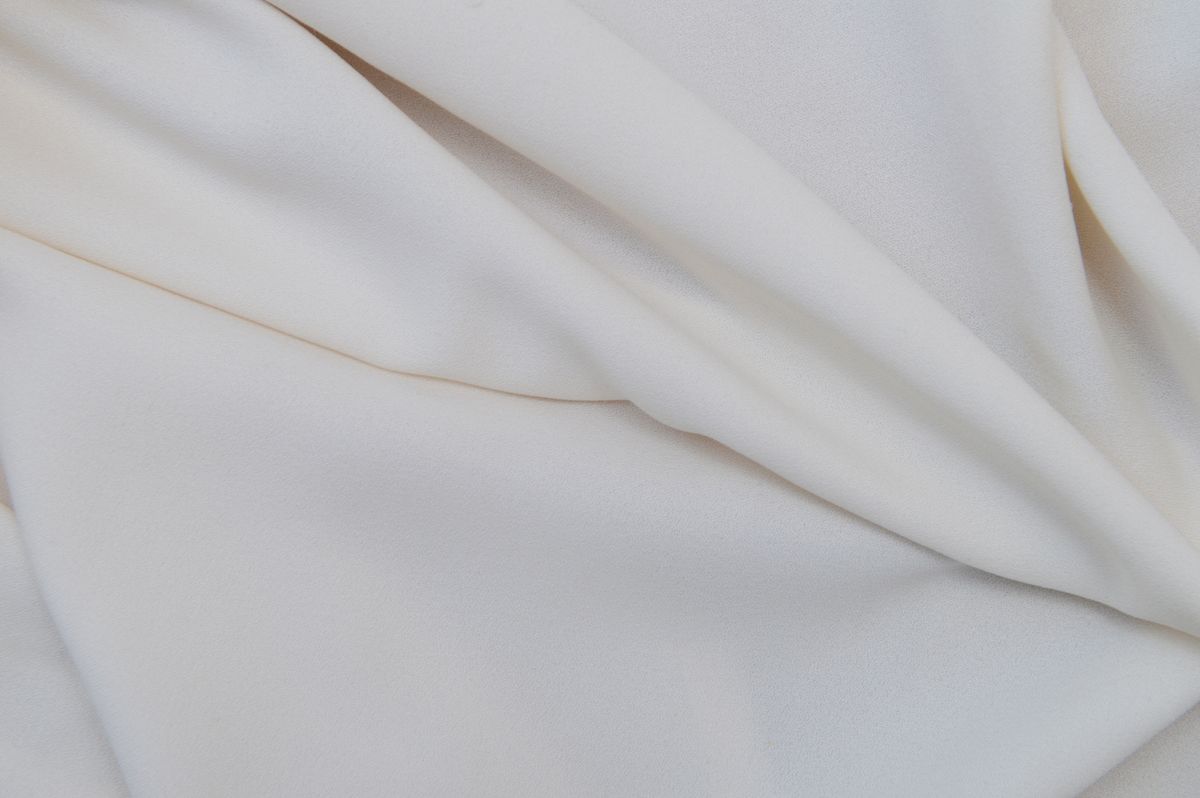 Smooth cream fabric in soft folds, showing the unbroken line a well-fitting cup gives under clothes